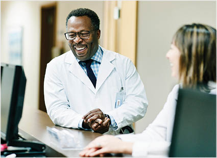 Laughing doctor in discussion with colleagues in hospital