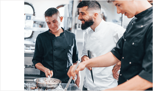 Group of people cooking food at kitchen together. Busy day at work.